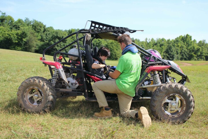 Kid in ATV with staff member.