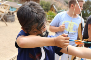Boy shooting bow and arrow.