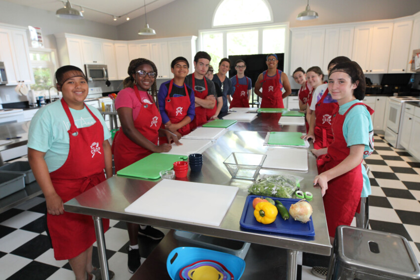 Kids posing in kitchen wearing aprons.