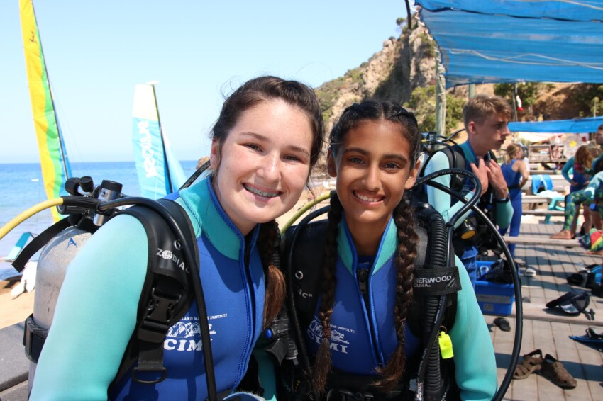 Two girls in scuba gear smiling.