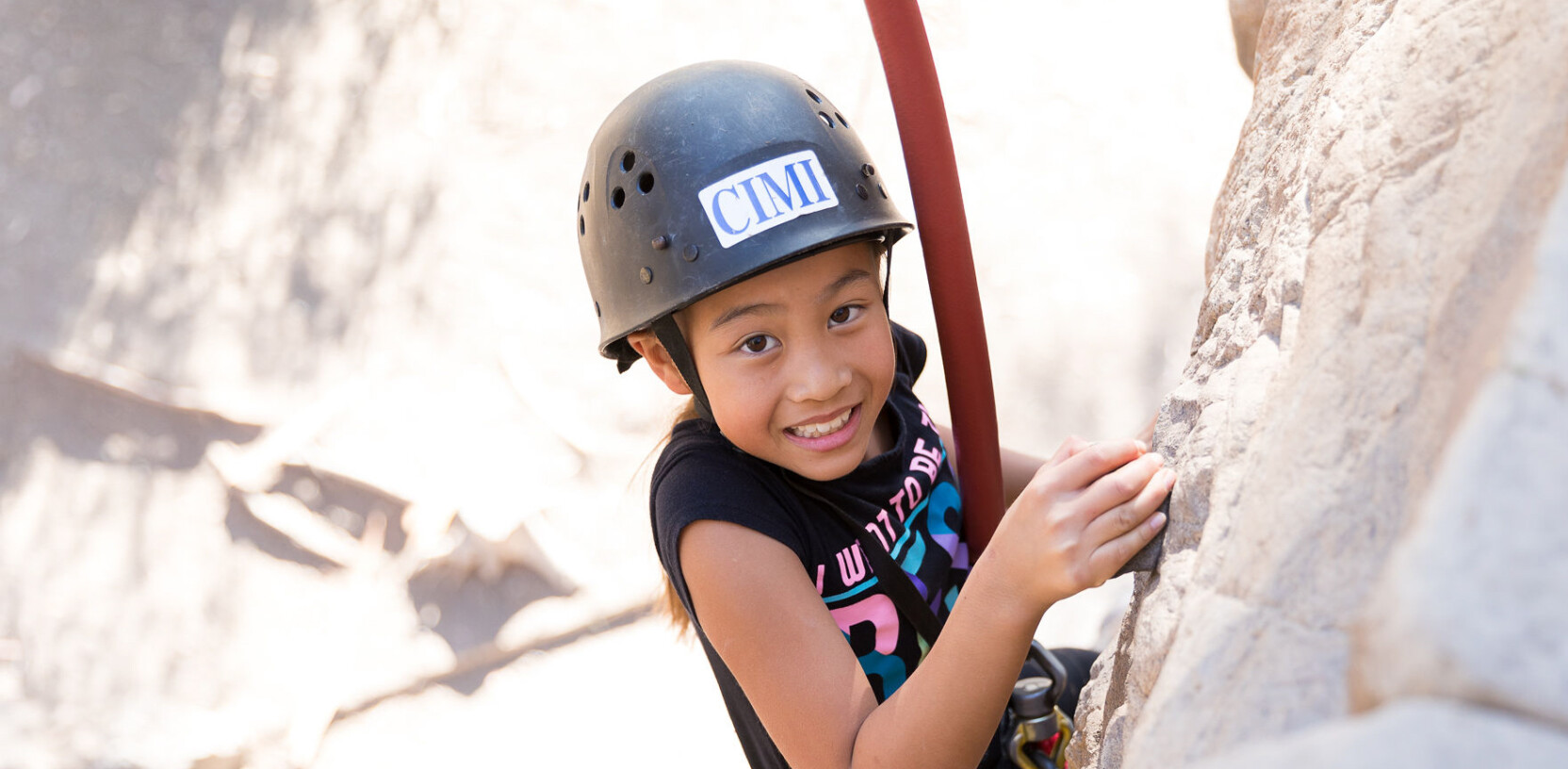 Girl rock climbing smiling.