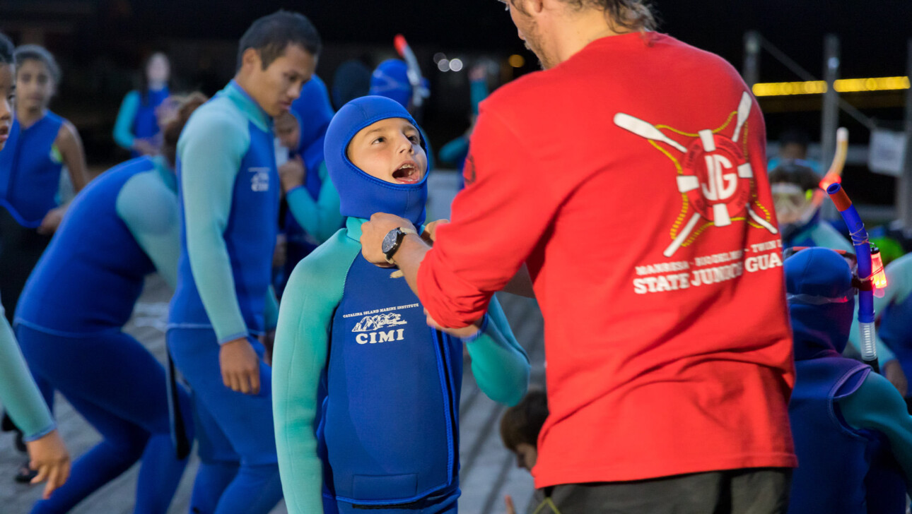 Staff helping boy with wetsuit.